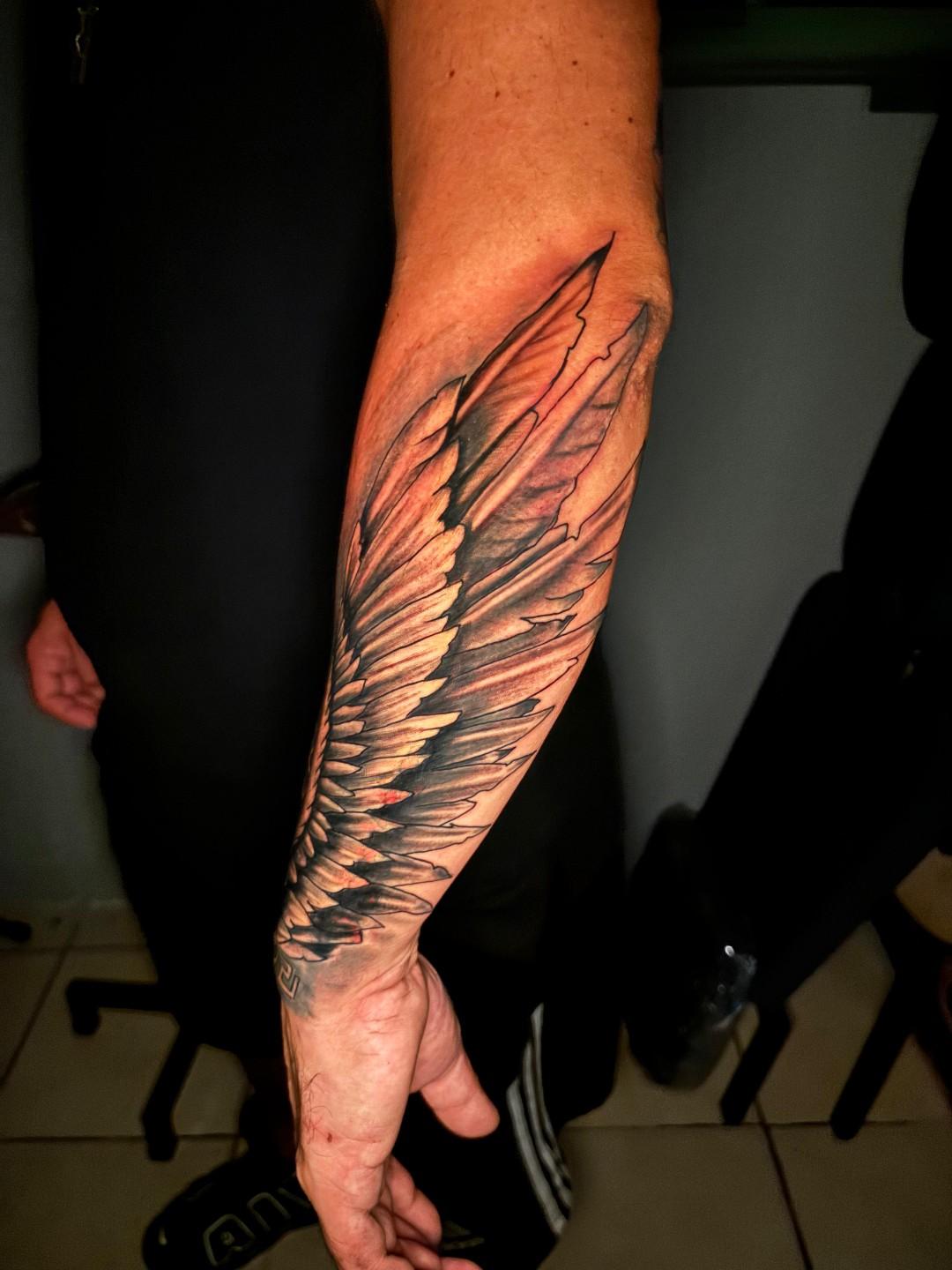 Tatuaje de alas realista en antebrazo